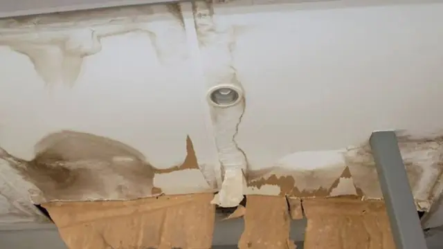 Water-stained, peeling ceiling around a light fixture with sagging material